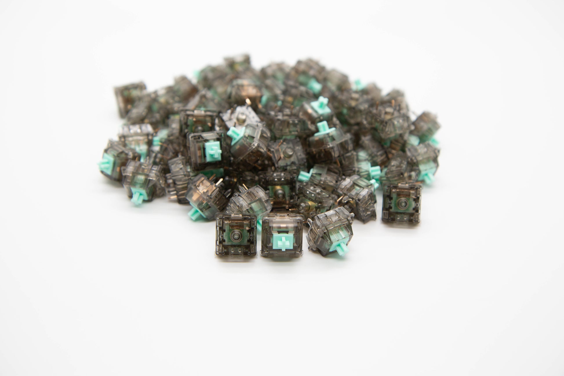 Close-up shot of a pile Durock Linear-62 g mechanical keyboard switches featuring gray transparent housing and teal stems