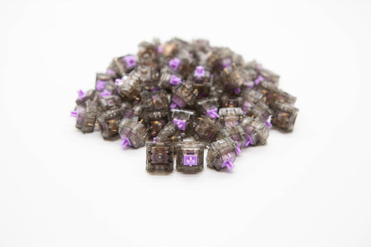 Close-up shot of a pile of Durock Linear-67 g mechanical keyboard switches featuring gray transparent housing and light purple stems